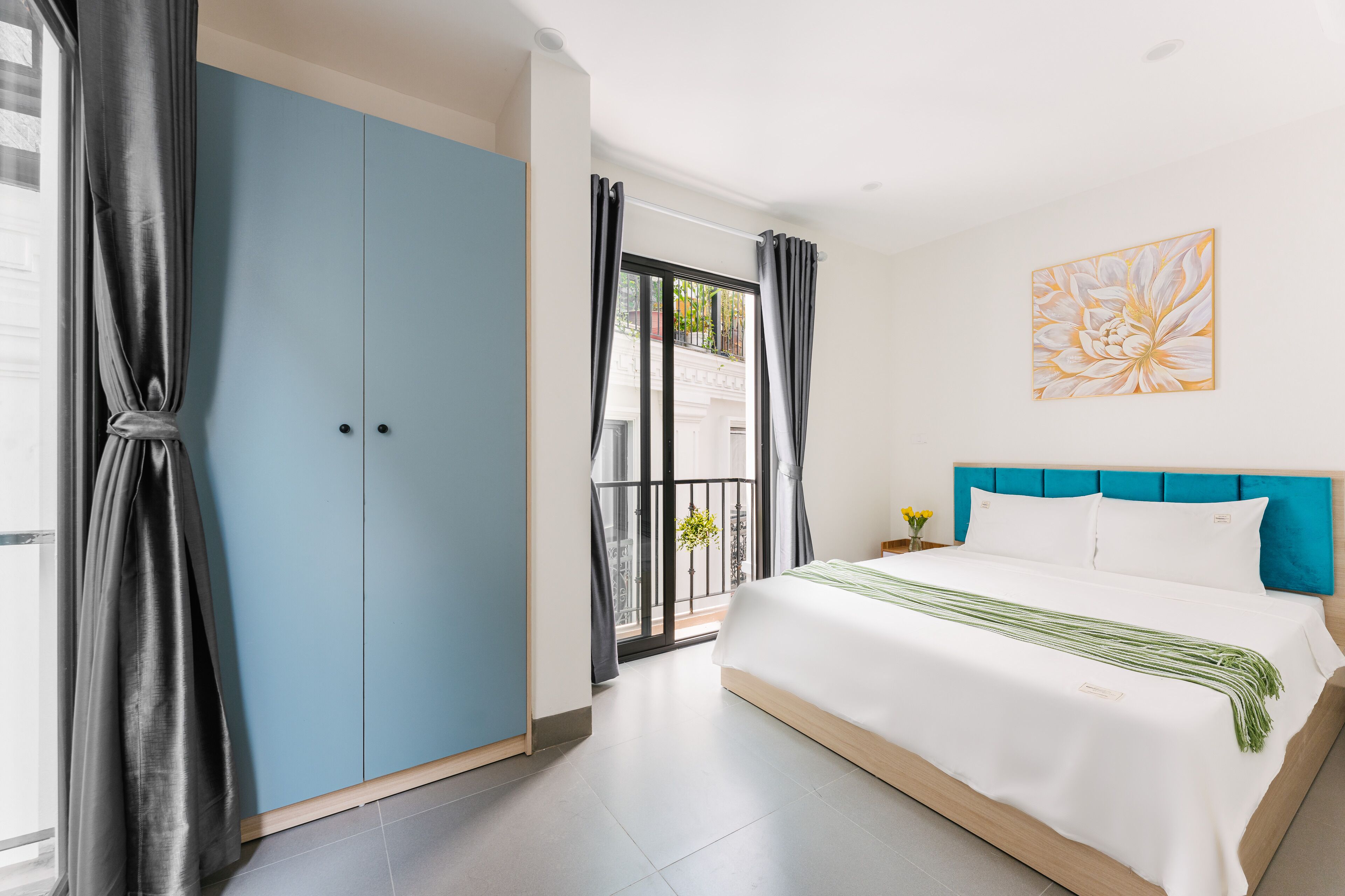 A bedroom with a large bed, a blue wardrobe, and a balcony with a view.