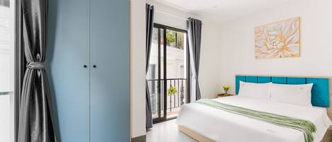 A bedroom with a large bed, a blue wardrobe, and a balcony with a view.
