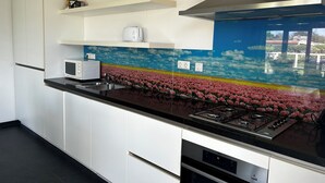 A modern kitchen with white cabinets, a black countertop, a gas stove, and a microwave.