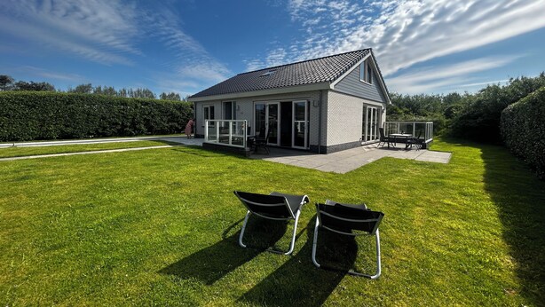 A modern house with a patio, a covered outdoor seating area, and a well-maintained lawn.