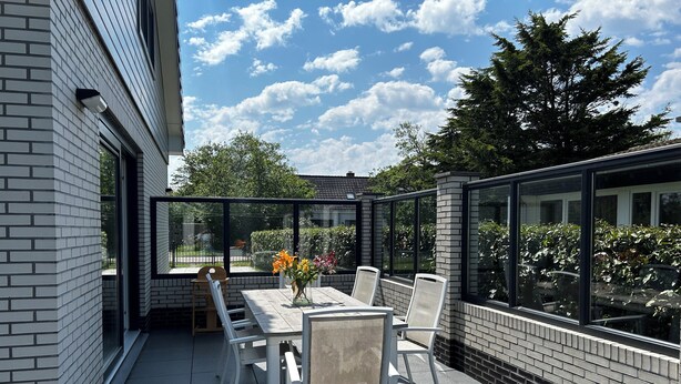 Une terrasse extérieure avec une table et des chaises, un vase rempli de fleurs et une vue sur les environs.
