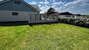 Une maison moderne avec une façade en briques, une grande baie vitrée et une pelouse bien entretenue.