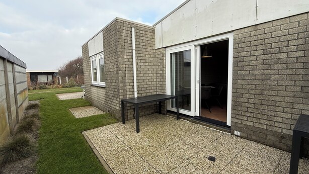 A modern house with a brick exterior, a gravel patio, and a small table.