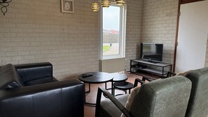 A living room with a TV, leather sofa, and a dining table.