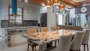 Una cocina moderna con encimera de granito, estufa integrada y comedor con mesa y sillas de mármol.