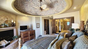 A bedroom with a large bed, a fireplace, a television, and a ceiling fan. - 8th Floor Penthouse with View of Sea in Resort with 8 Pools (Puerto Peñasco)