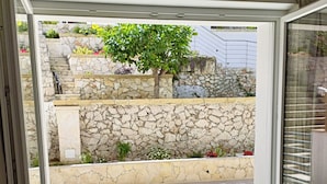 A modern outdoor patio with stone walls and a tree.
