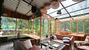 Une pièce chaleureuse et bien éclairée, avec des meubles en bois, de grandes fenêtres et une table en verre.