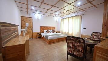 A hotel room with a wooden bed, a desk, a chair, and a window with curtains.