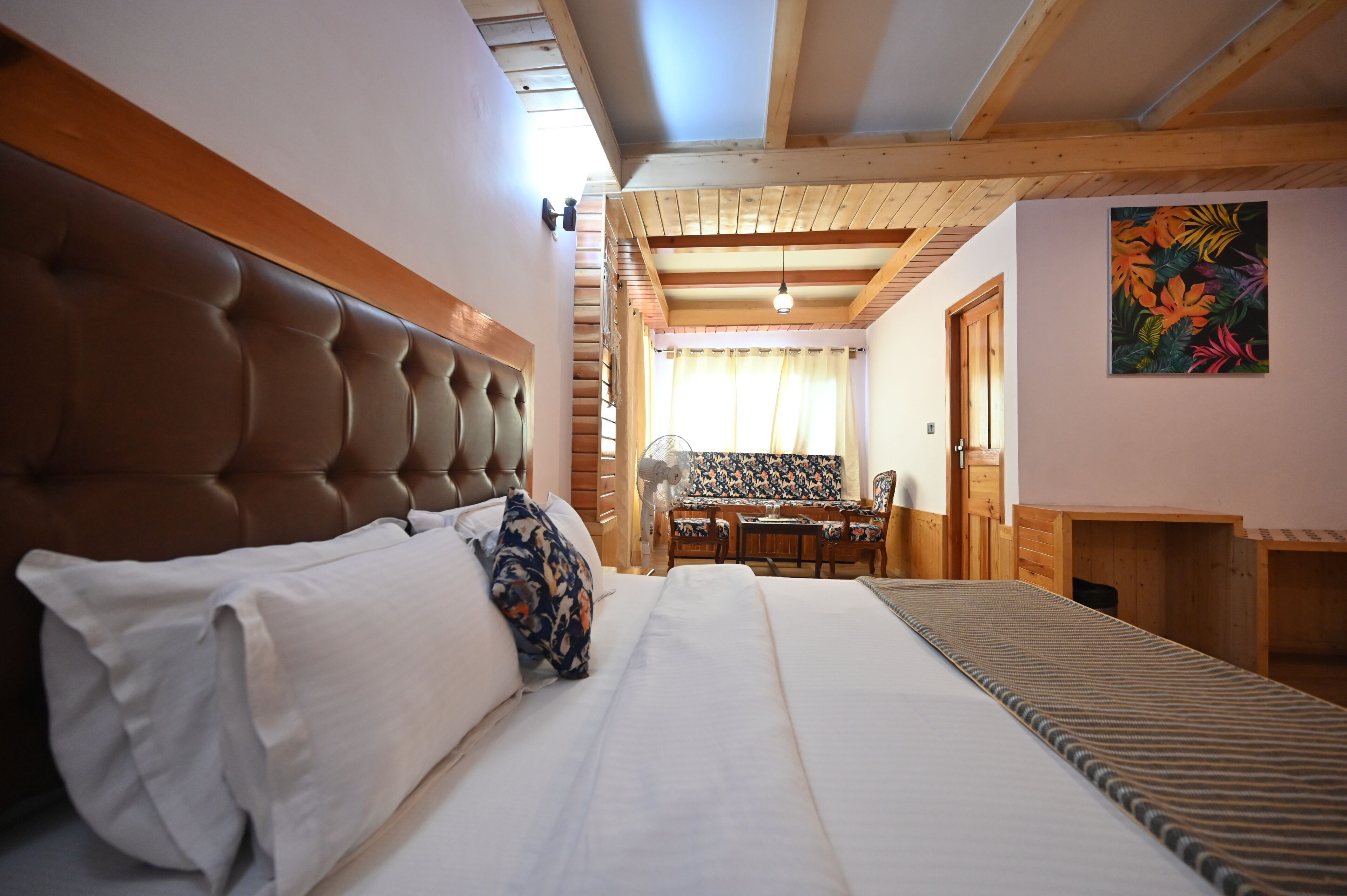 Una camera da letto con un letto grande, travi in legno a soffitto, un'area pranzo e un camino.