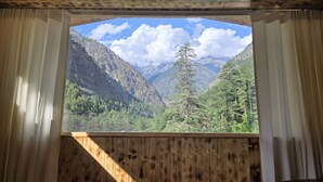 Une pièce dotée d’un plafond en bois et d’une grande fenêtre donnant sur un paysage montagneux.