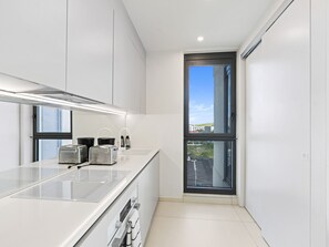 A modern kitchen with a large window, a built-in oven, and a stainless steel countertop. - B-905 (Cupecoy)