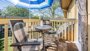 Une terrasse avec une table et des chaises, un parasol et une vue sur les environs.