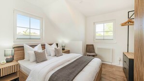 Une chambre à coucher comprenant un lit, des tables de chevet, une chaise, un radiateur et une armoire.