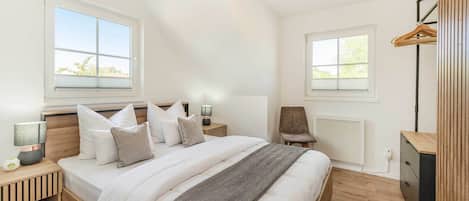 A bedroom with a bed, bedside tables, a chair, a radiator, and a wardrobe.