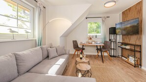 Un salon moderne comprenant un canapé, une table à manger, des chaises, un téléviseur et une bibliothèque.
