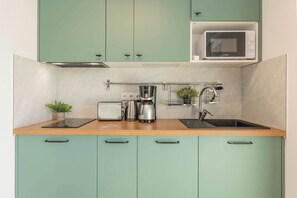 A kitchen with teal cabinets, a microwave, a toaster, a kettle, and a sink. - Ferienwohnung Strandliebe in Koserow - Romantik und Meer für Zwei (Koserow)
