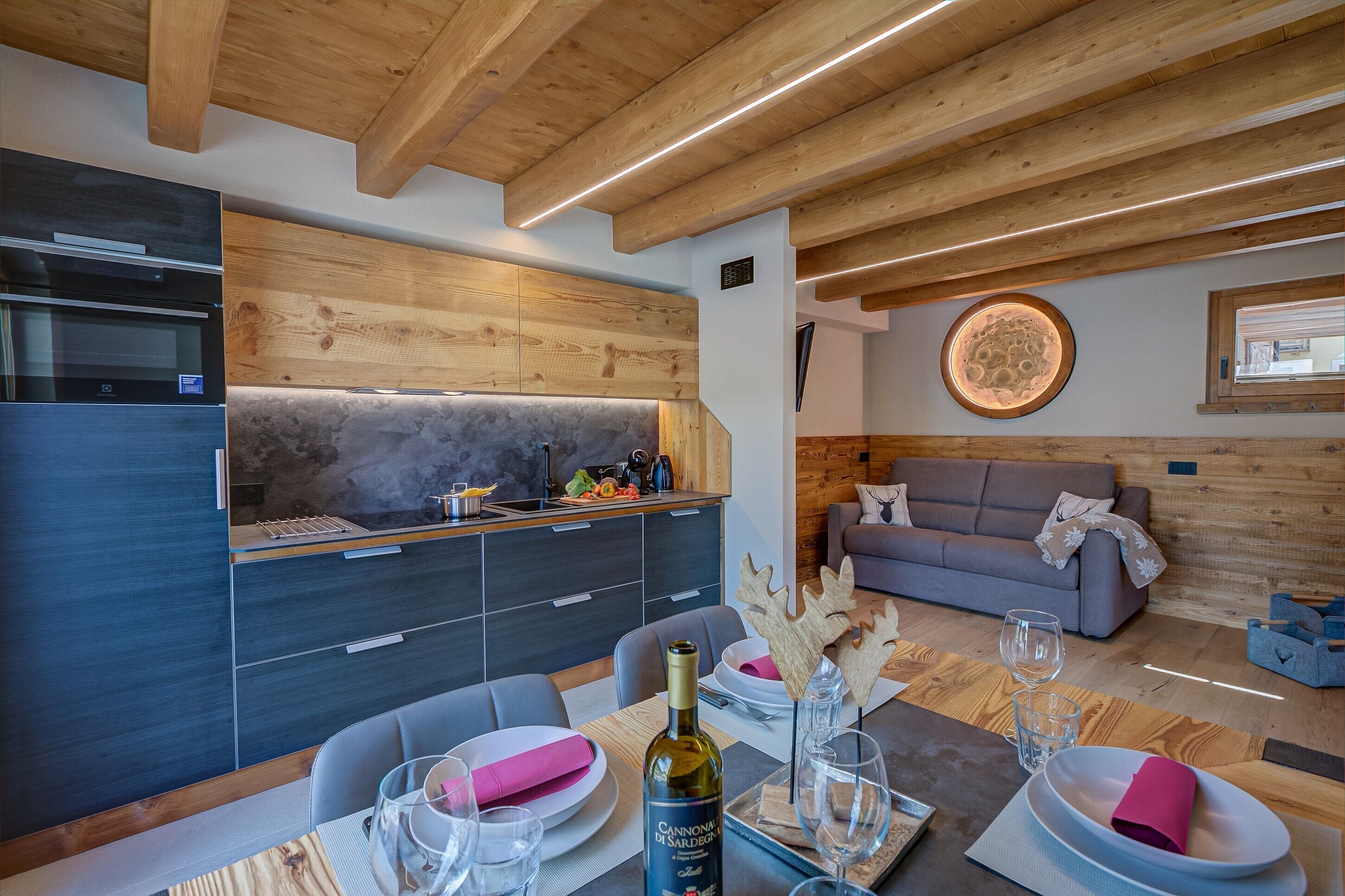 A modern kitchen with built-in appliances, a dining area with a table set for two, and a cozy living space with a sofa.