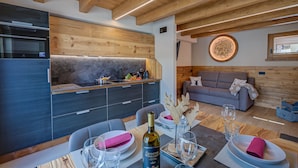 A modern kitchen with built-in appliances, a dining area with a table set for two, and a cozy living space with a sofa. - Belfiore (Livigno)