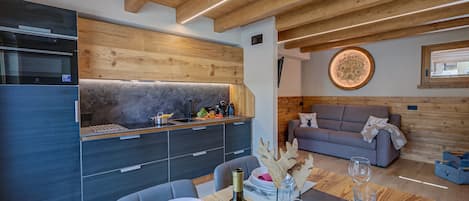 Una cocina moderna con electrodomésticos integrados, un comedor con una mesa lista para dos personas y una sala de estar acogedora con un sofá.