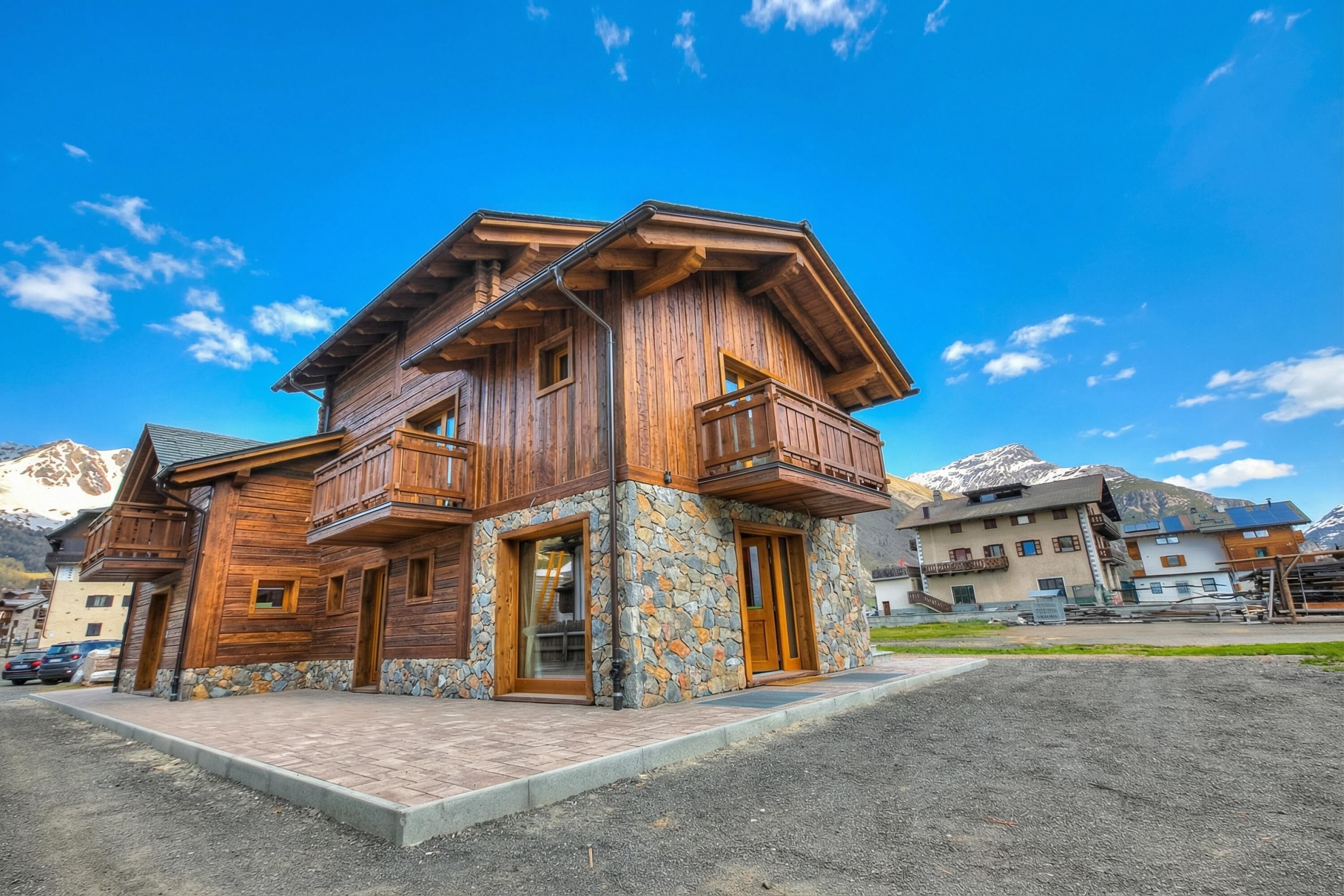 A wooden house with a stone foundation, wooden balconies, and a mountain backdrop.