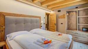 A bedroom with a large bed, wooden headboard, and a wooden wardrobe. - Casa Fiorita (Livigno)
