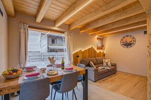 A cozy dining area with a wooden table set for two, a sofa, and a mountain-themed wall decoration. - Casa Fiorita (Livigno)