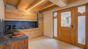 A kitchen with wooden cabinets, a marble countertop, and a wooden door with frosted glass panels. - Casa Fiorita (Livigno)