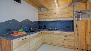 A kitchen with wooden cabinets, a marble backsplash, and a built-in oven. - Casa Fiorita (Livigno)