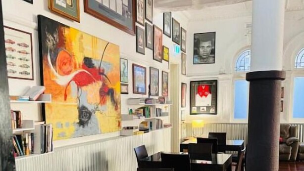 A dining area with a long table and chairs, surrounded by walls adorned with framed pictures and artwork.