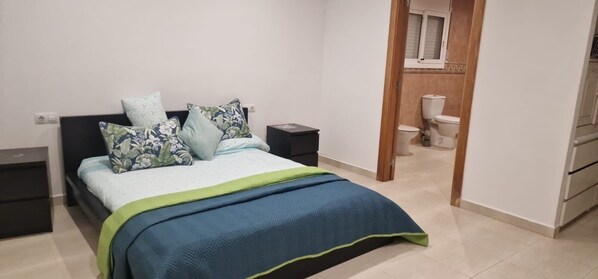 A bedroom with a bed, nightstands, and a view of the bathroom. - Casa en la Montaña Cerca de la Playa (Barcelona)
