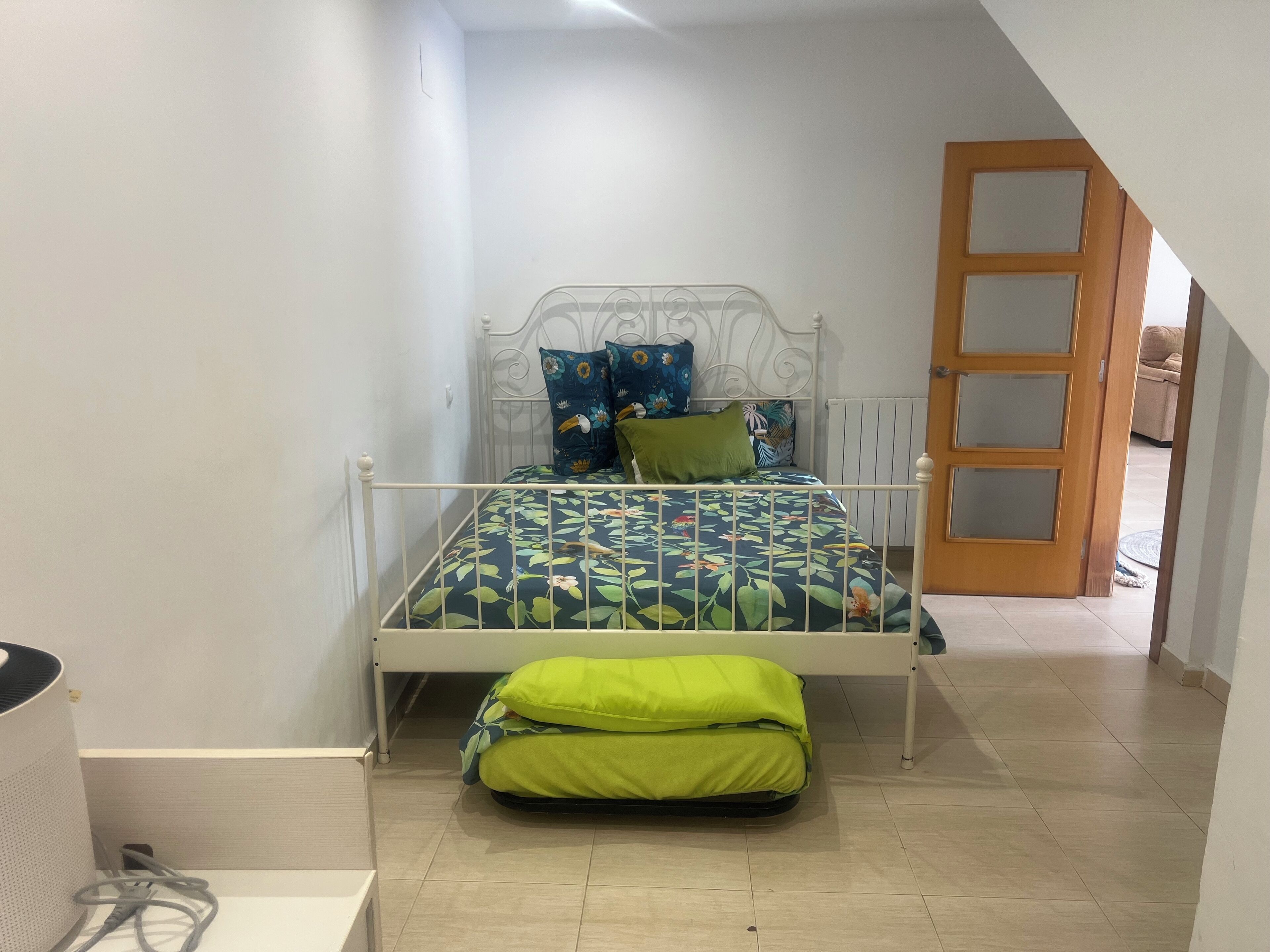 A bedroom with a bed, pillows, a radiator, and a door.