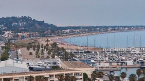 A marina with numerous boats docked, a beach with people, and buildings in the background. - Casa en la Montaña Cerca de la Playa (Barcelona)