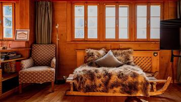 L’intérieur d’un chalet chaleureux, avec un lit en bois, un fauteuil à motifs et une bibliothèque.