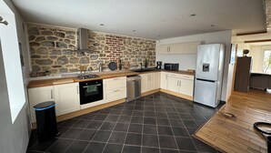 A modern kitchen with stone walls, a black tiled floor, and wooden countertops.