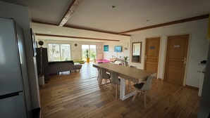 A spacious kitchen with wooden flooring, a dining table, and a refrigerator.