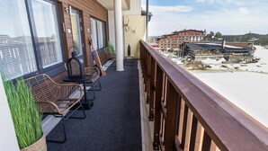 En balkong med flätade stolar och utsikt över ett område med hotell och andra turistattraktioner.