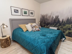 A bedroom with a bed, a nightstand, a lamp, and a forest mural on the wall. - Casa krogerus ruka by Interhome (Kuusamo)