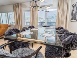 A modern meeting room with a glass table, multiple chairs, and a view of a balcony with blinds.