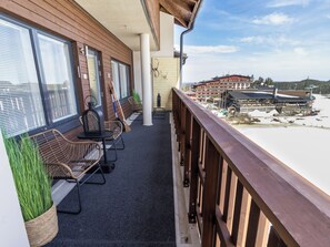 A balcony with wicker furniture, a view of a building with a ski lift, and a snowy landscape.