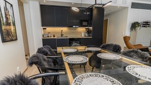 Ett modernt kök med mörka skåp, en köksö och en matplats med runda bord och stolar.