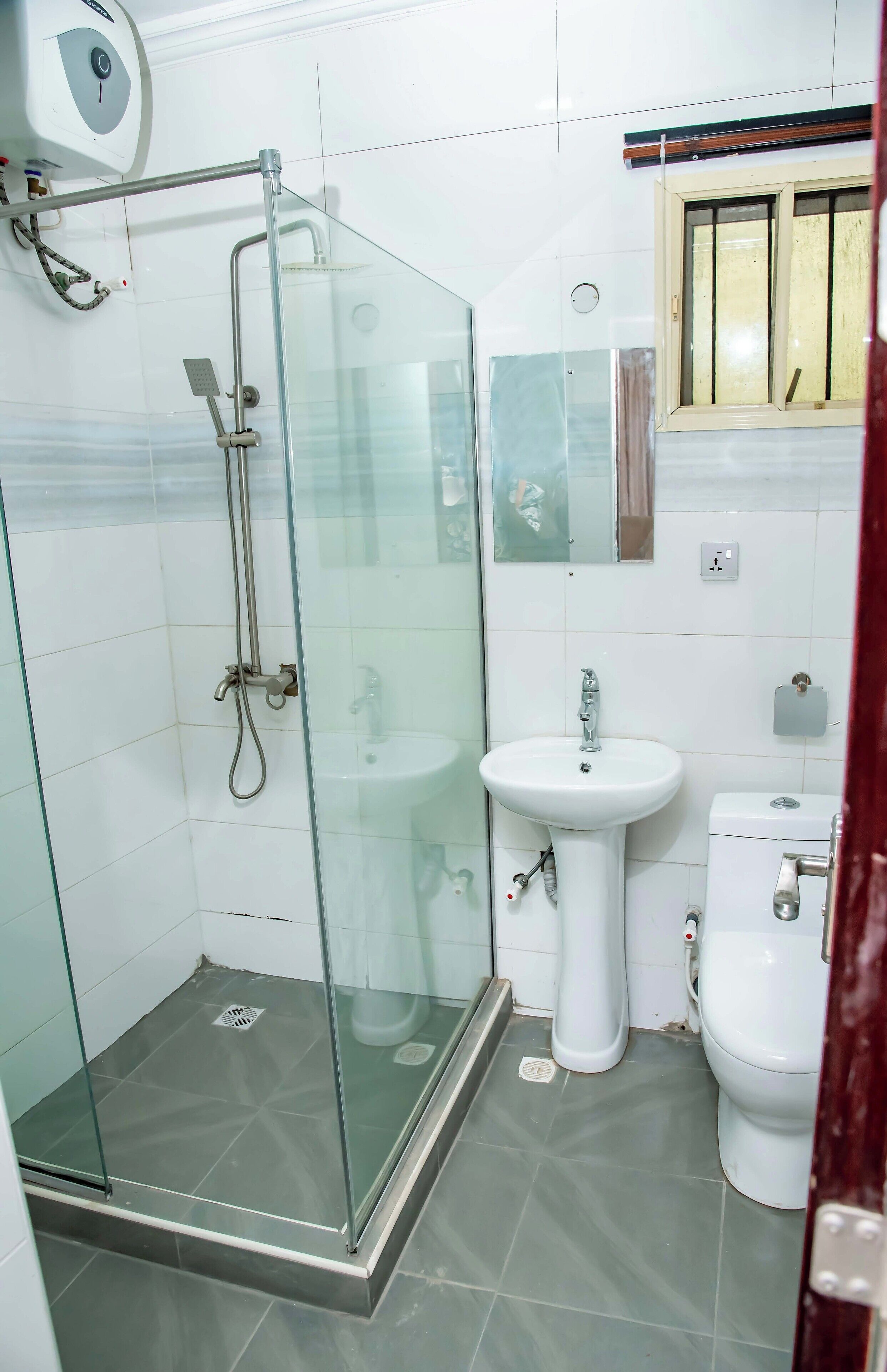 A bathroom with a glass-enclosed shower, a white sink, and a toilet.
