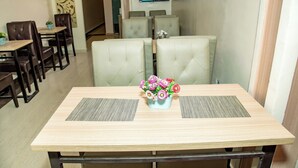 A dining area with a wooden table, two cushioned booths, and a television mounted on the wall. - Everland Hotel and Suites (Ojodu Berger)