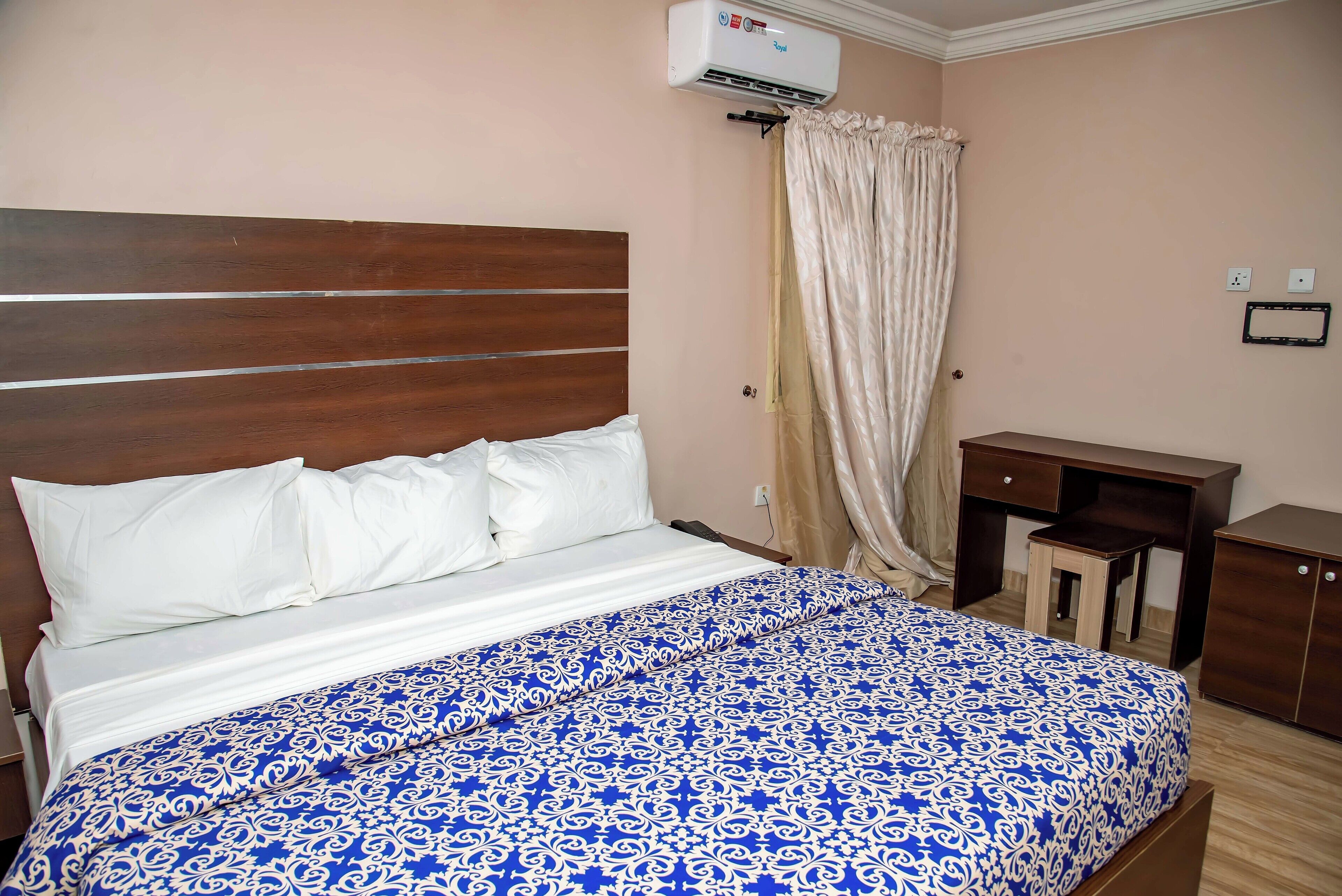 A bedroom with a bed, a wooden headboard, a desk, and a wardrobe.