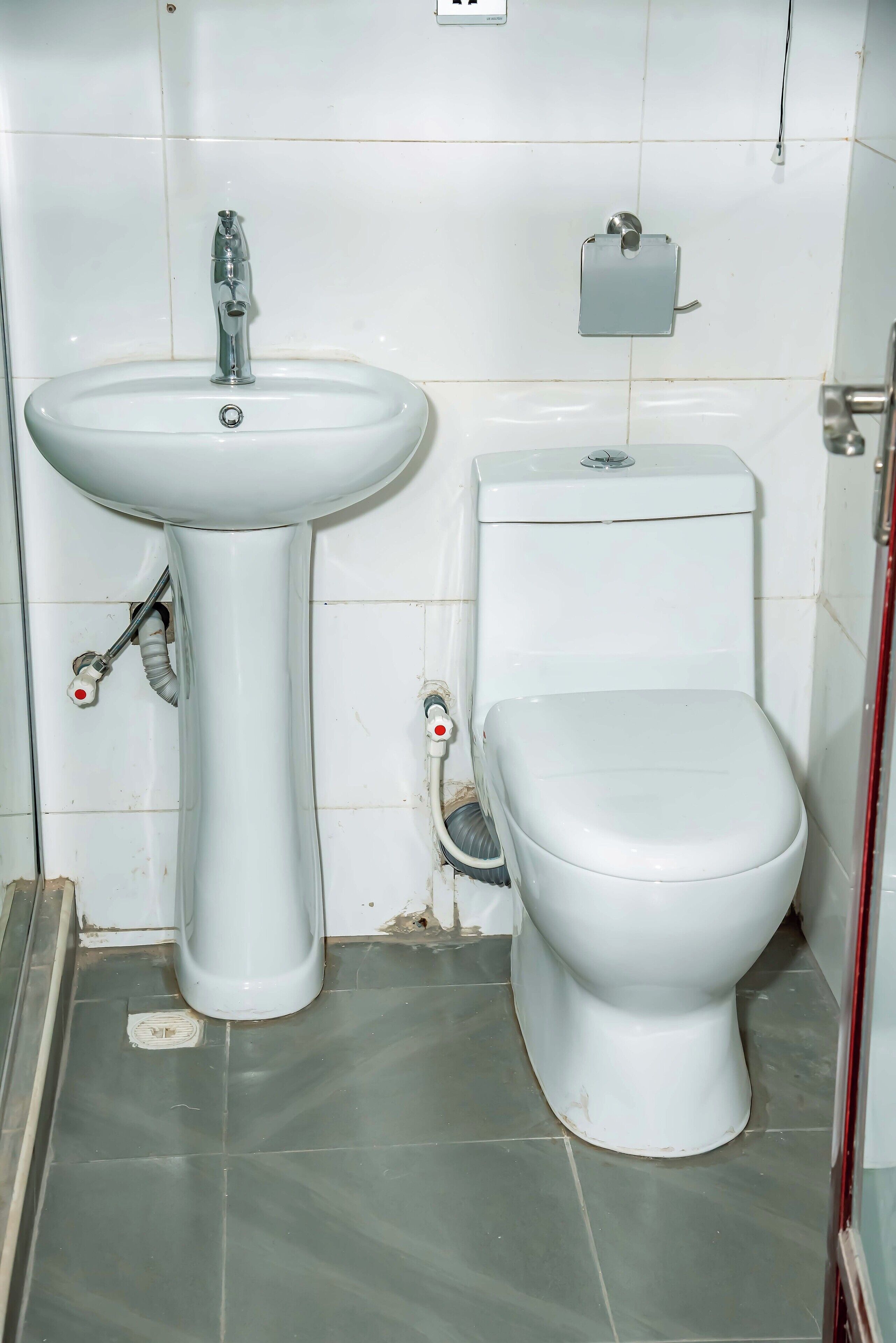 A bathroom with a white sink, toilet, and a small trash bin.