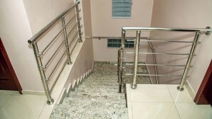 A staircase with metal handrails and a small window with wooden shutters. - Everland Hotel and Suites (Ojodu Berger)