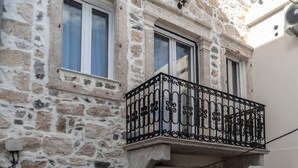 Un edificio de piedra con dos ventanas y un balcón con barandillas de metal decorativas.