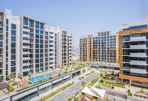 Un edificio residencial moderno con varios pisos, piscina en la azotea y un patio ajardinado.