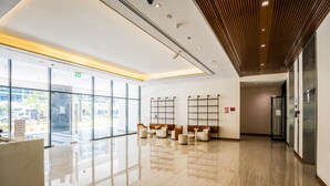 A modern lobby with a glass wall, seating area, and a reception desk. - Zapbed House - AR 533 (Dubai)