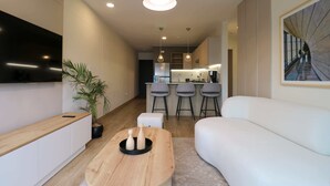 A modern living room with a sofa, a wooden coffee table, and a TV mounted on the wall.